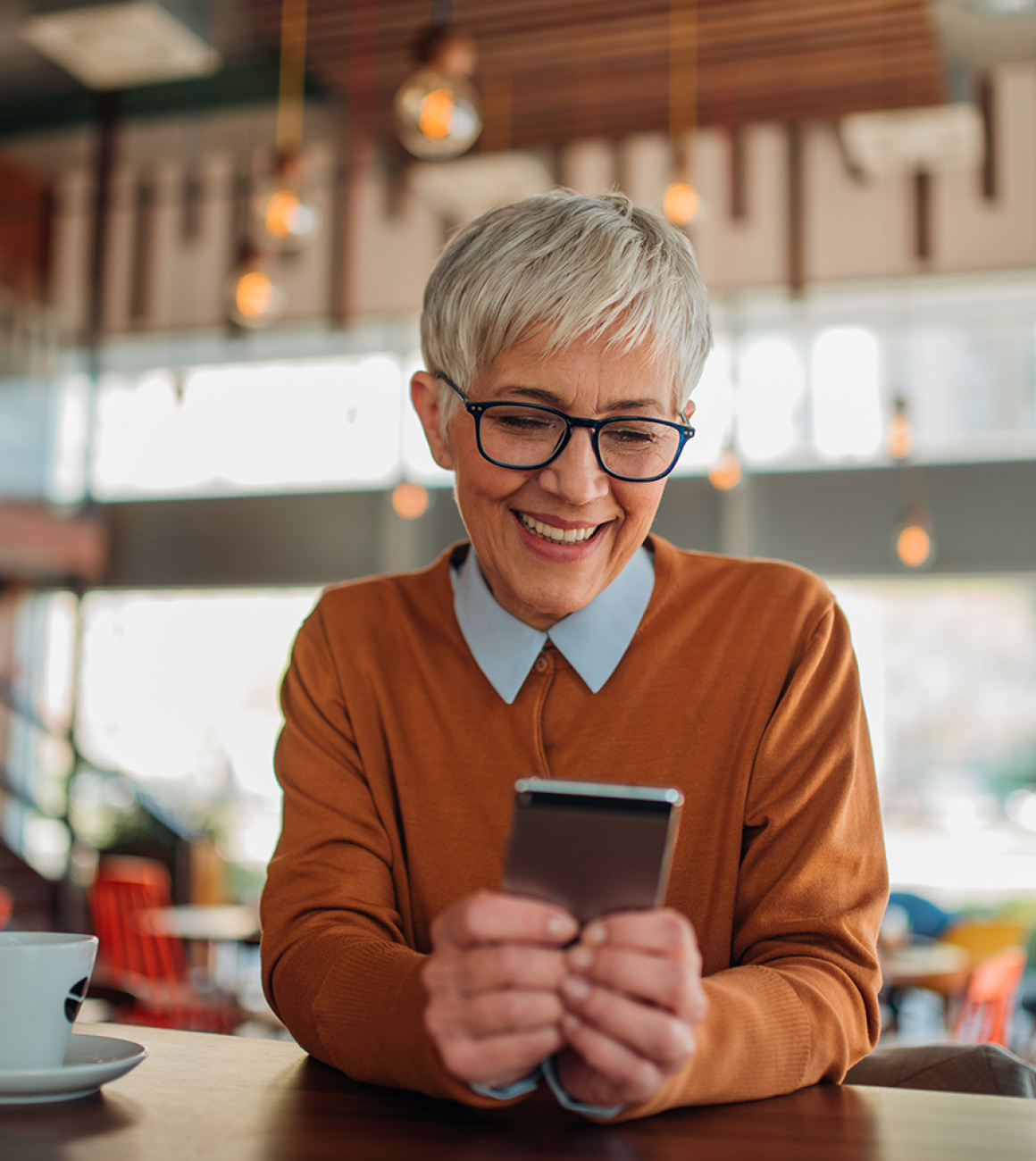 Une dame d'une cinquantaine d'années veille sur son aîné via son smartphone et l'application mobile OtioCare